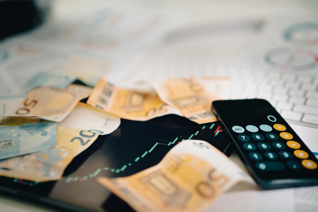 pexels-photo-27075161-27075161 Euro banknotes scattered on a trading chart with a calculator, symbolizing finance and analysis.